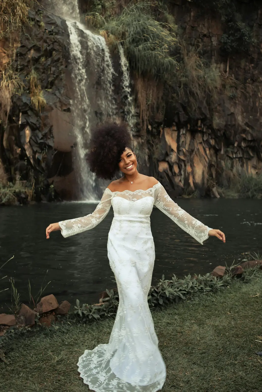 Bride in a flowing white gown smiling during an outdoor portrait session