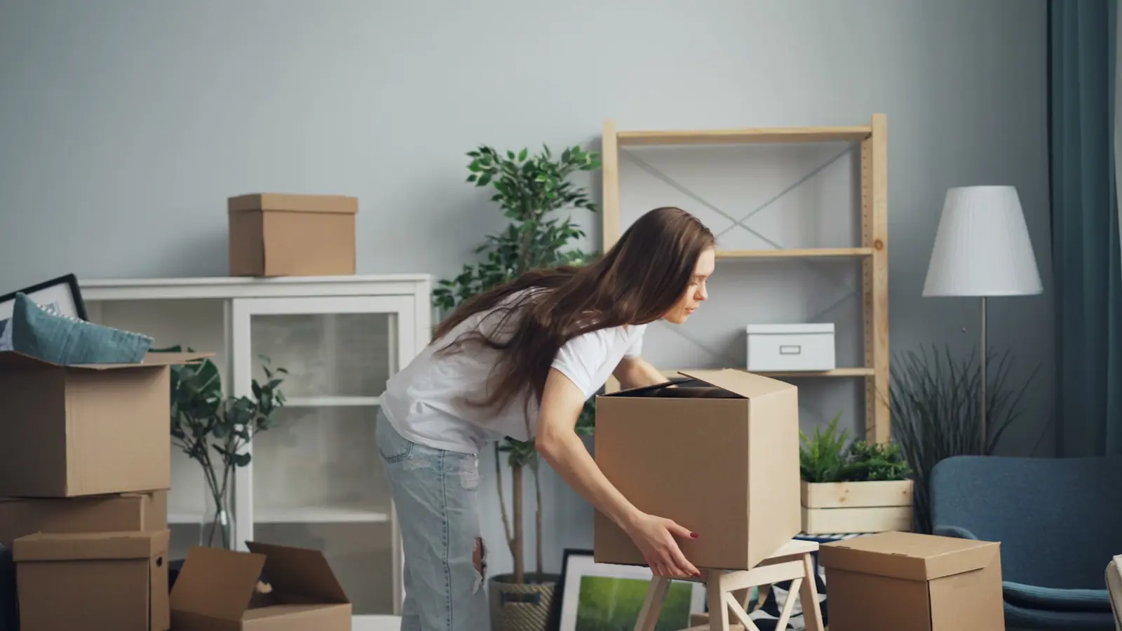 Moving-day entrepreneur rolling a stack of boxes across a home studio