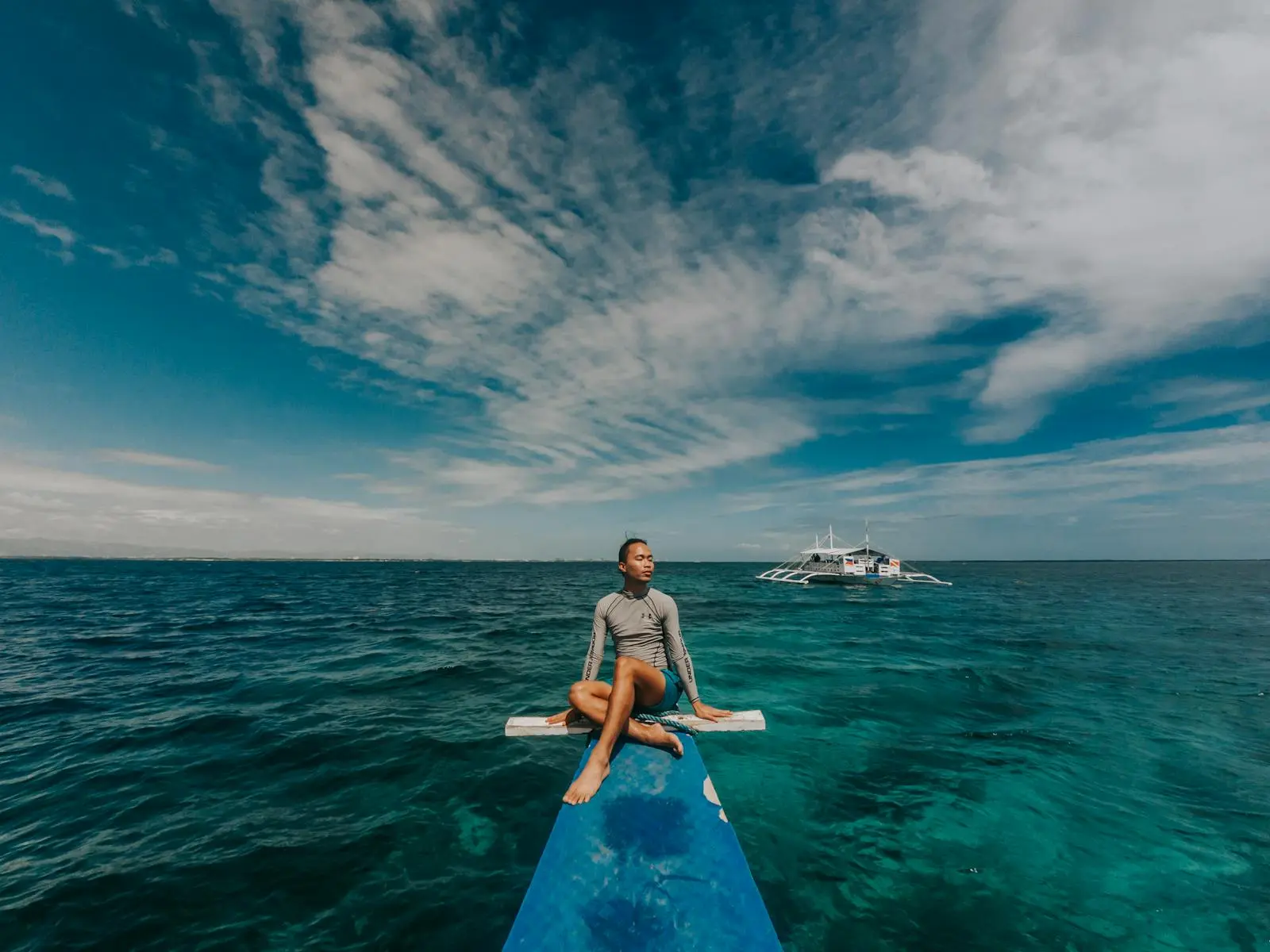 Traveler relaxing beside an infinity pool overlooking tropical water